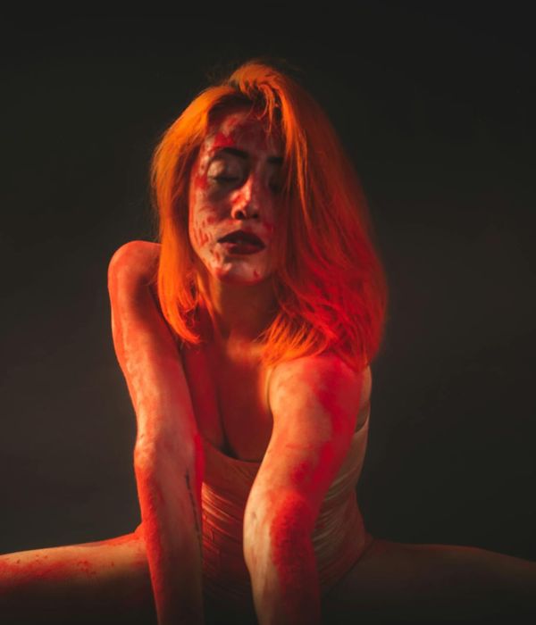 Woman performing a graceful yoga stretch in a dark studio.